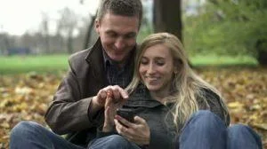stock-footage-happy-couple-with-smartphone-in-autumn-park