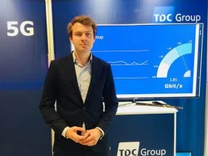 TDC Groups koncernstrategidirektør Lasse Pilgaardstår foran fartmåleren, der viser de høje hastigheder fra 5G-testen. (foto: TDC)