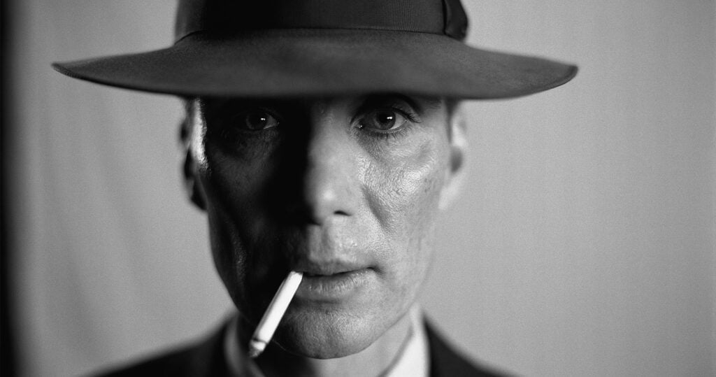 et billede fra filmen "oppenheimer" med en mand med hat og en smøg i munden