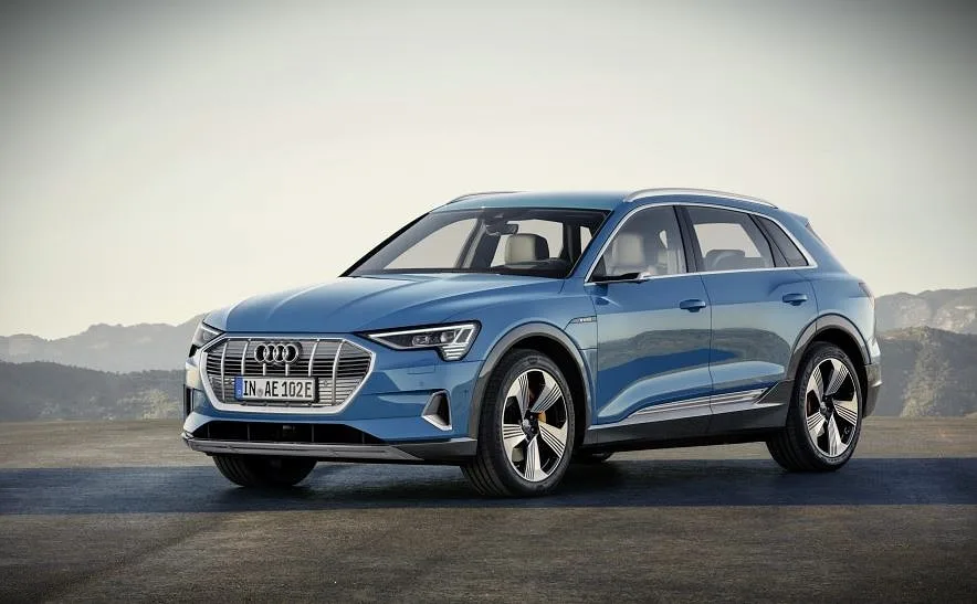 Sølvgrå Audi e-tron 55 elbil parkeret på en grusvej i et åbent landskab.