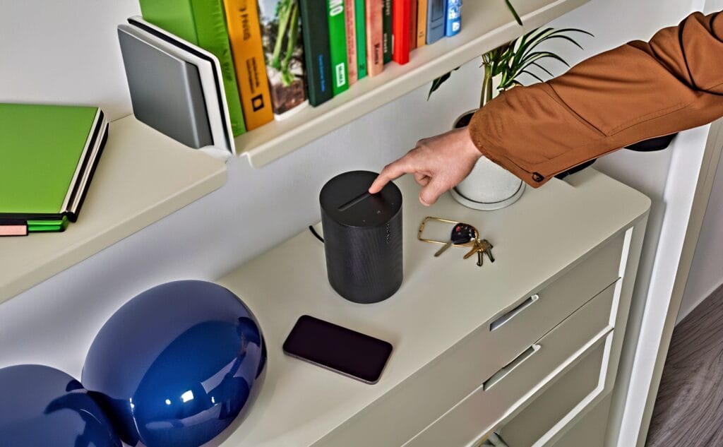 Sonos Era 100 SL højttaler i sort og hvid finish placeret på et bord.
